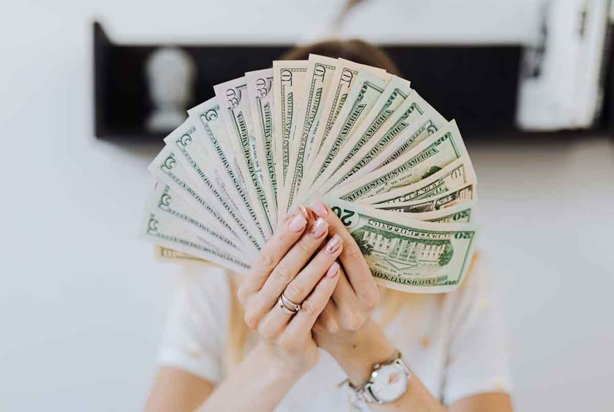 دست خانمی که پول ها را پروانه ای جلو صورتش گرفته