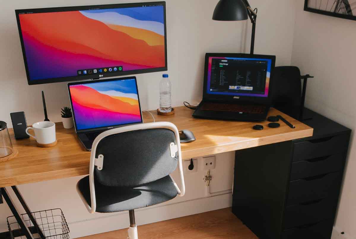 لپ تاپ روی میز کامپیوتر به همراه صندلی و کشو