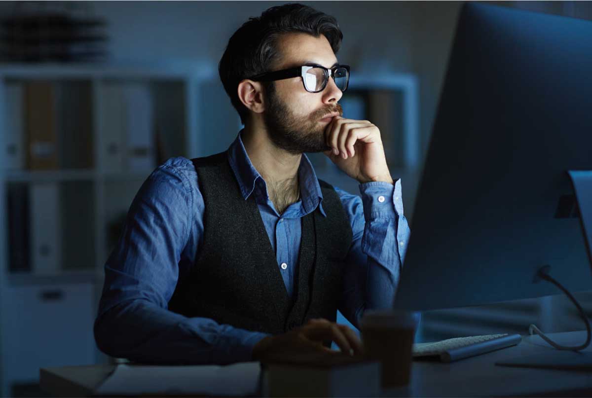 اقای عینکی که ژیله پوشیده و یک دستش زیر چونشه ودر حال کار کردن با کامپیوتره