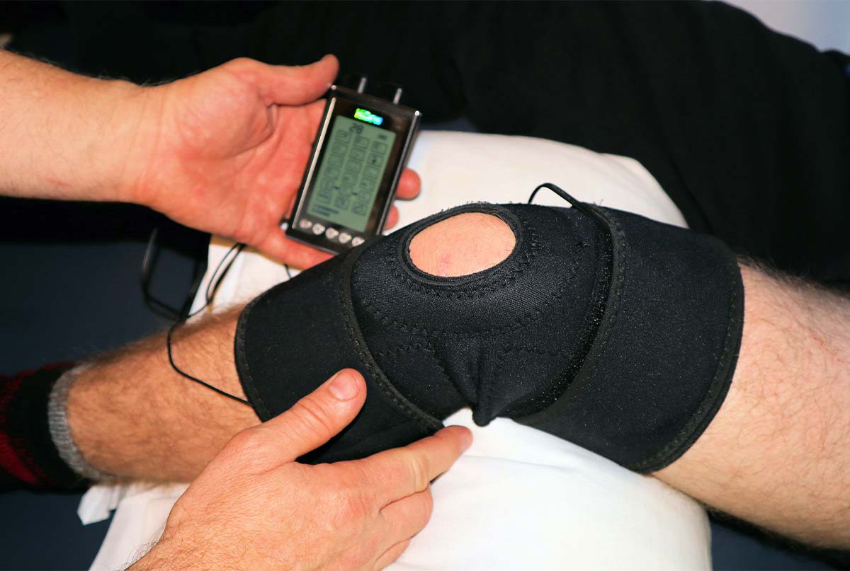 دکتری که با دستگاه مخصوص پای بیمار را فیزیوتراپی میکند