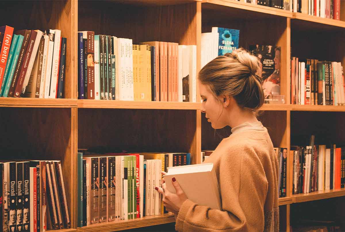 دختری در کتابخانه در حال انتخاب کتاب
