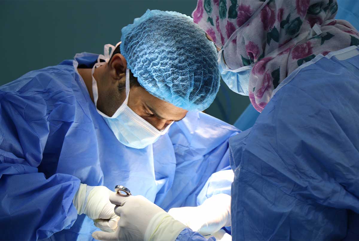 جراح هایی که گان ابی پوشیدن و در حال جراحی در اتاق عمل هستن