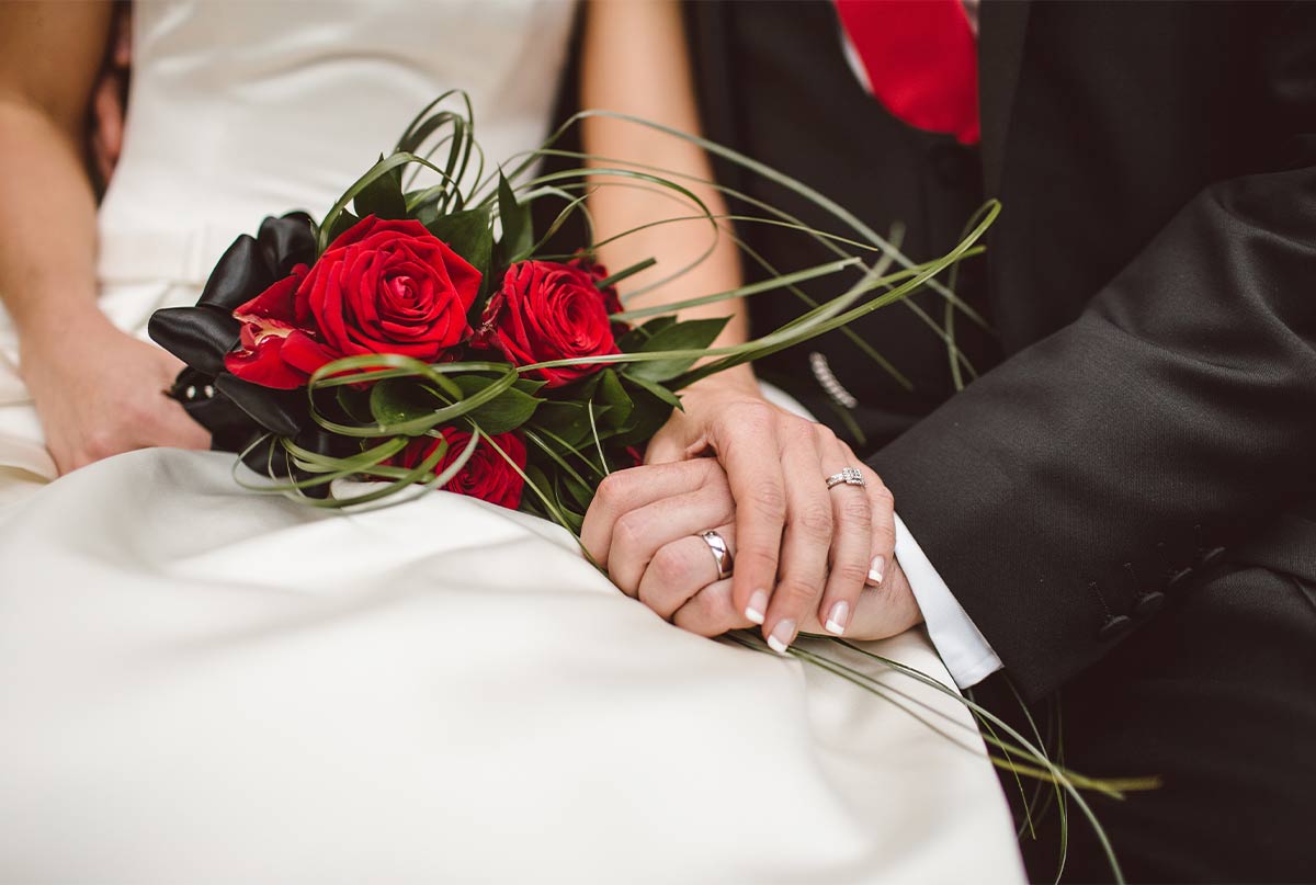 عروس ودامادی که دست همدیگه رو گرفتن و دسته گل عروس رز قرمزه