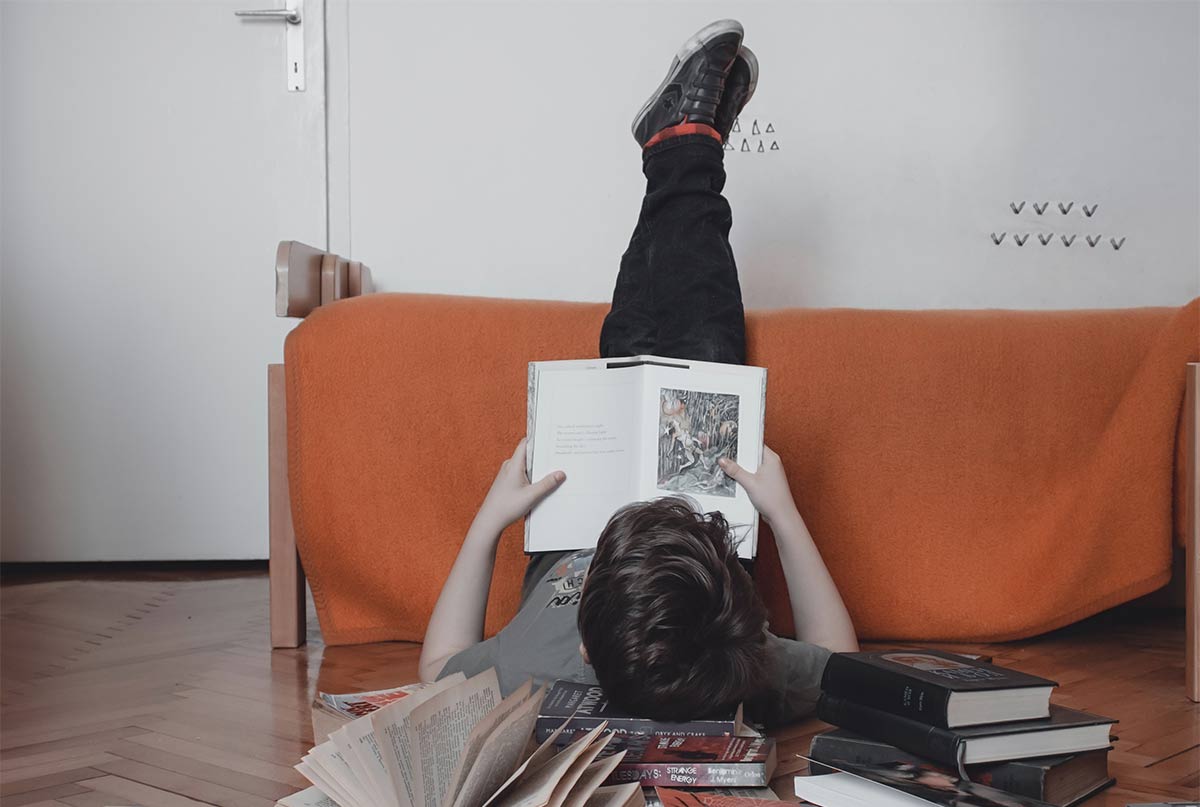 اقایی که دراز کشیده پاهاش رو به دیوار زده و داره کتاب میخونه و زیر سرش هم چندتا کتابه