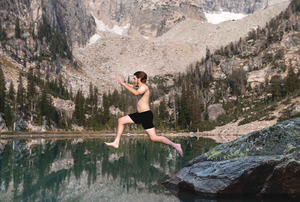 فرد ورزشکار بدون لباس درحال پریدن از صخره ها در طبیعتی زیبا