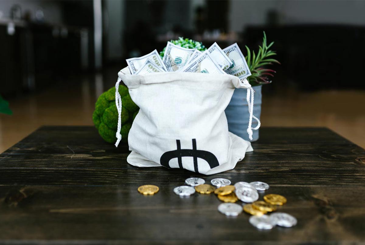 کیسه پر از سکه و دلار روی میز