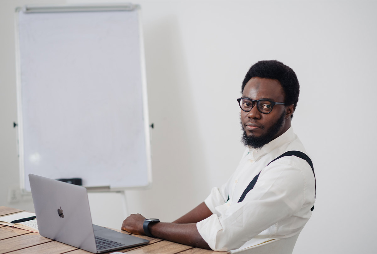 اقای سیاهپوست با پیراهن سفید پشت لپ تاپ 