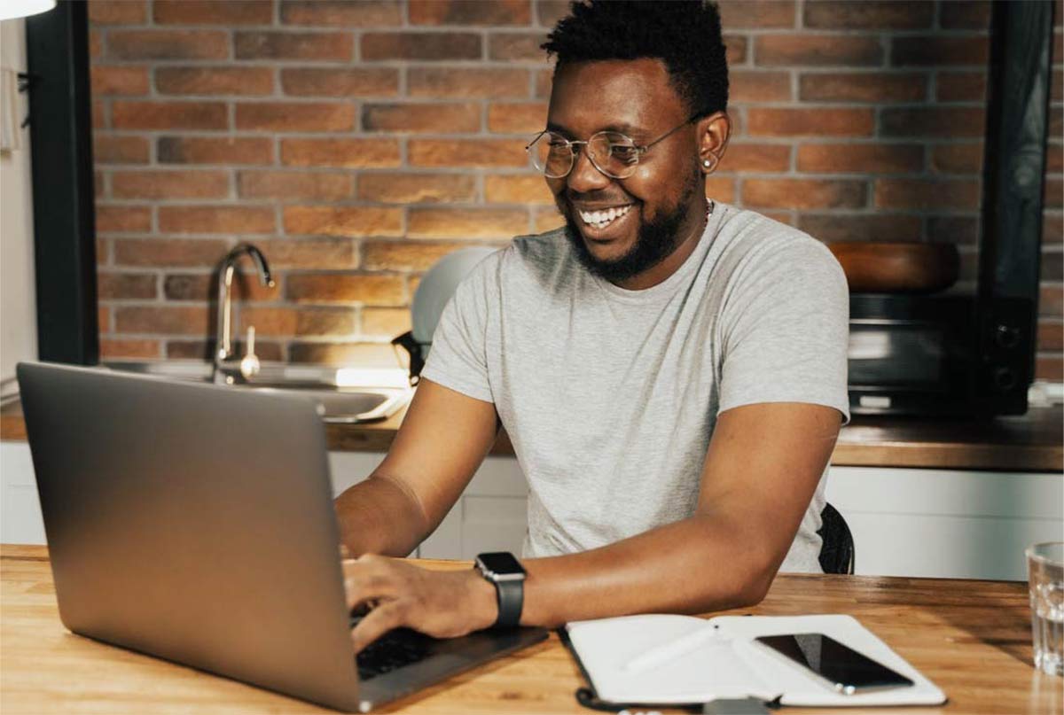 اقای سیاهپوستی که داره میخنده و با لپ تاپ کار میکنه
