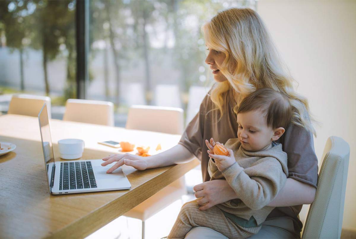 خانمی که بچه ای تو بغلشه و داره با لپ تاپ کار میکنه