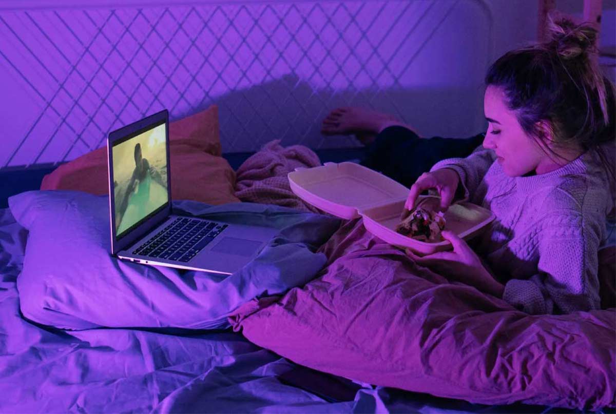 خانمی که تو تخت نشسته و داره تو لپ تاپ نگاه میکنه