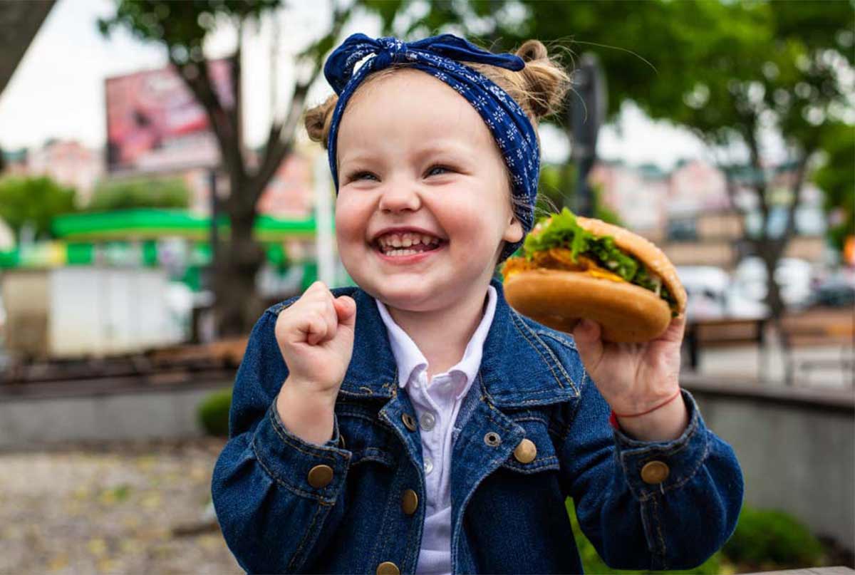 دختر بچه ای که همبرگر دستشه و میخنده